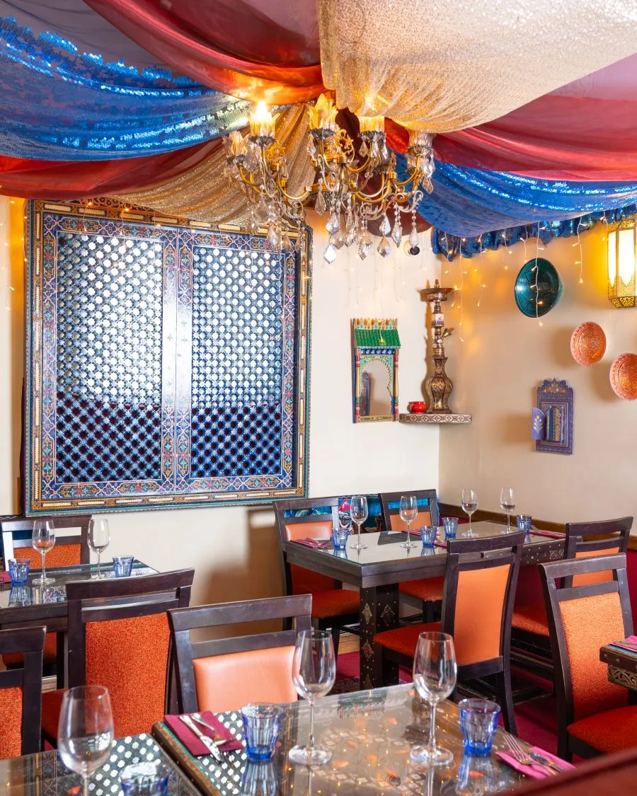 A dining table set under hanging fabric and a chandelier